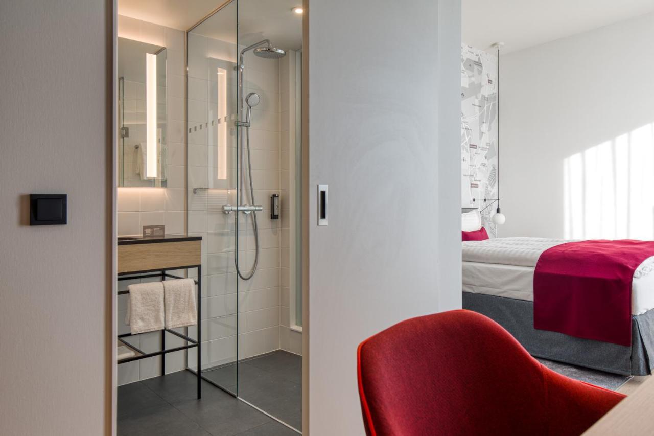 Intercityhotel Berlin Airport Ber Terminal 1 & 2 Schönefeld Extérieur photo The photo shows a modern hotel room or bathroom space. On the left, there is a glass-enclosed shower area with a sleek design, featuring a showerhead and minimalist fixtures. Adjacent to the shower, there's a sink area with a stylish countertop and a